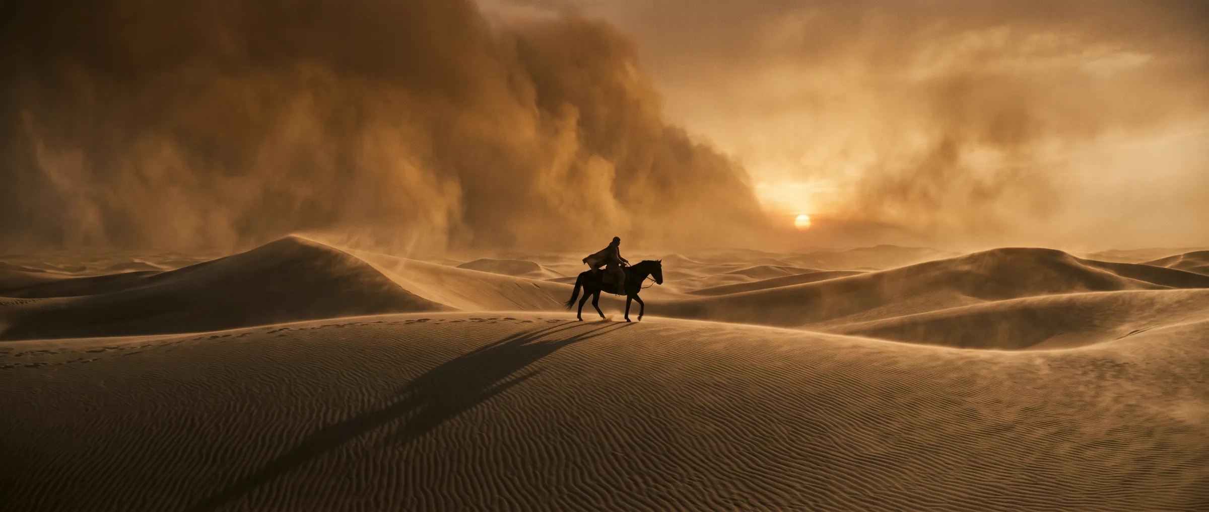 A rider crosses vast dunes ahead of an amber dust storm